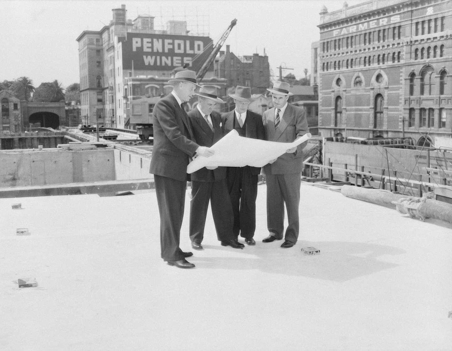 Construction managers review blueprints at an urban building site.
