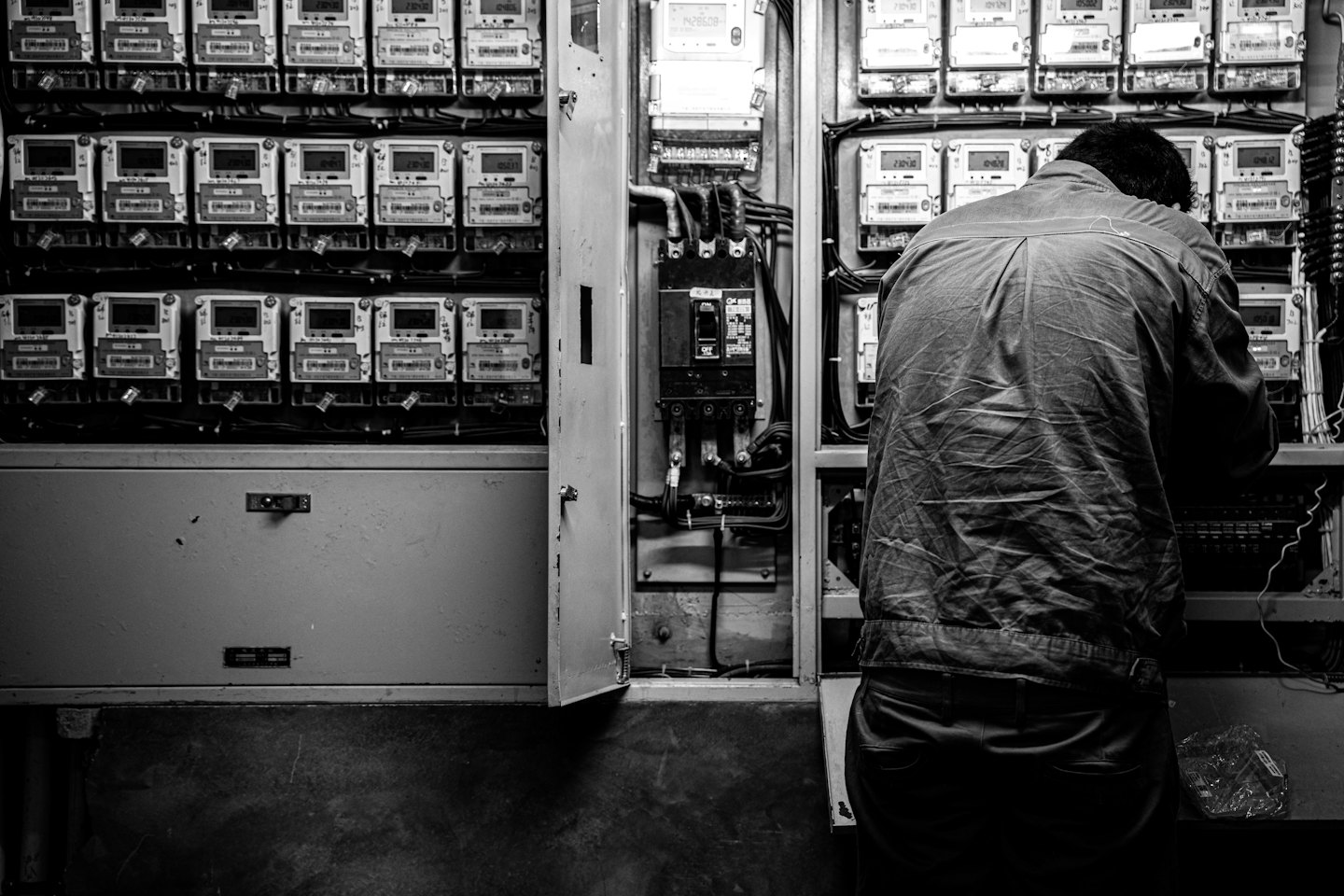 Person working on an open electrical panel with complex wiring.